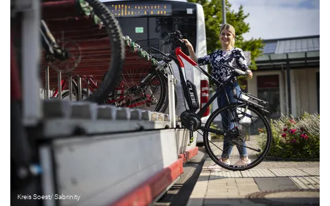 Mädchen läd ihr Rad auf den Anhänger am Fahrrradbus auf.