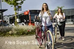 Zwei Mädchen schieben ihre Räder über den Bürgersteig am Busbahnhof