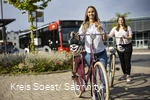 Zwei Mädchen schieben ihre Räder über den Bürgersteig am Busbahnhof